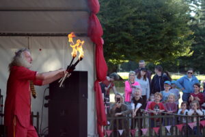 Man in red juggling fire in front of laughing children