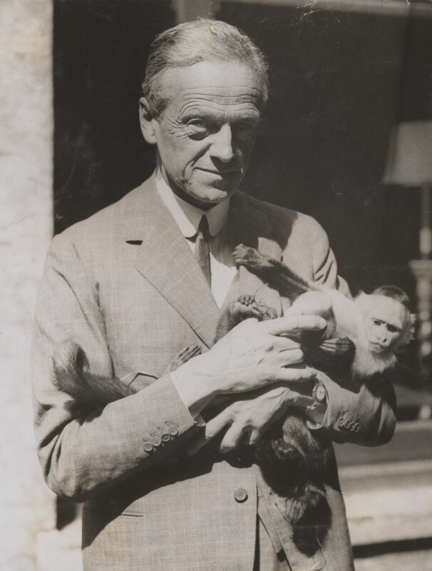 Black & white photo of Walter Edward Guinness 1st Baron Moyne holding a small monkey