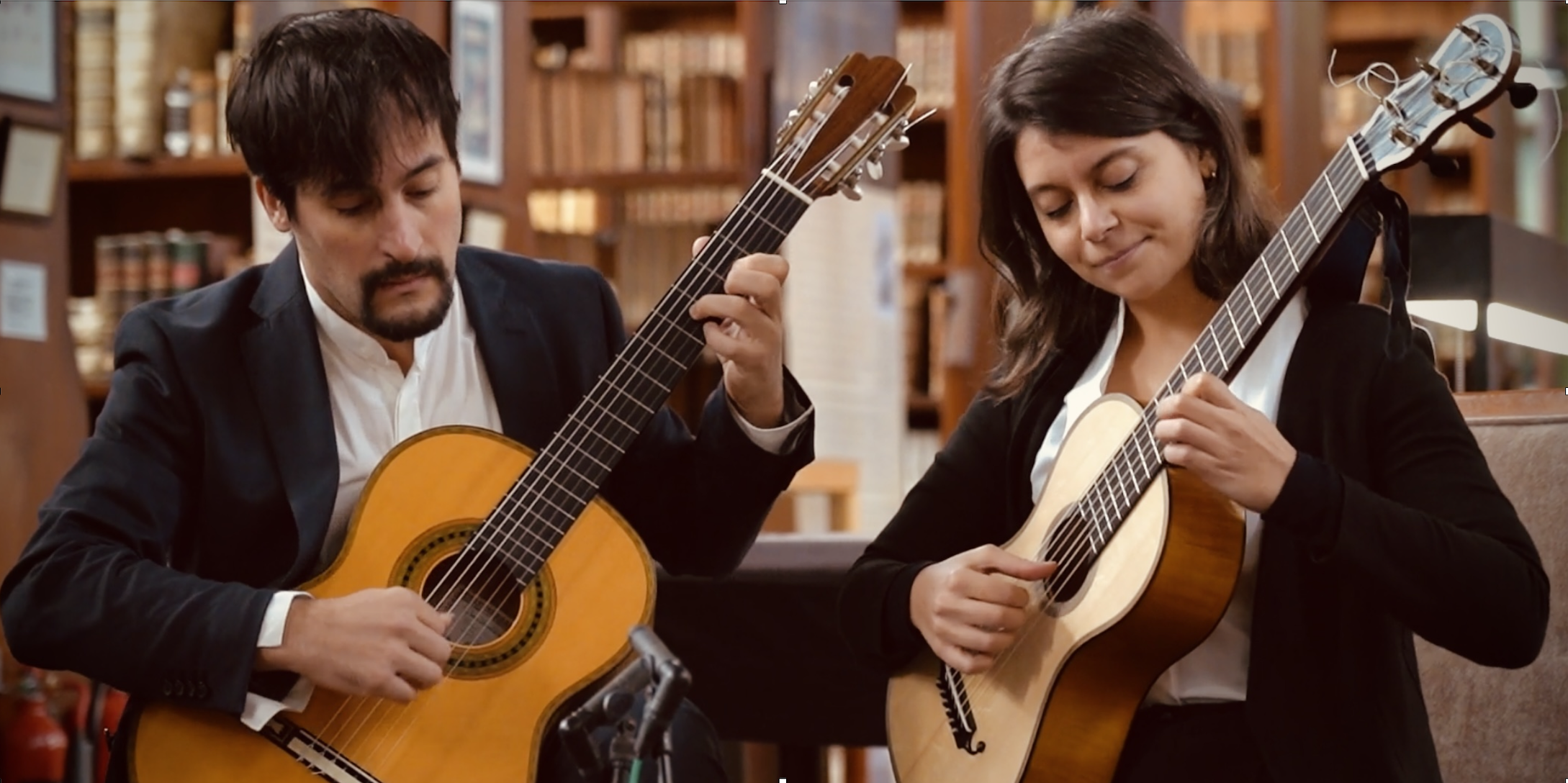 A man and a woman sitting playing guitars