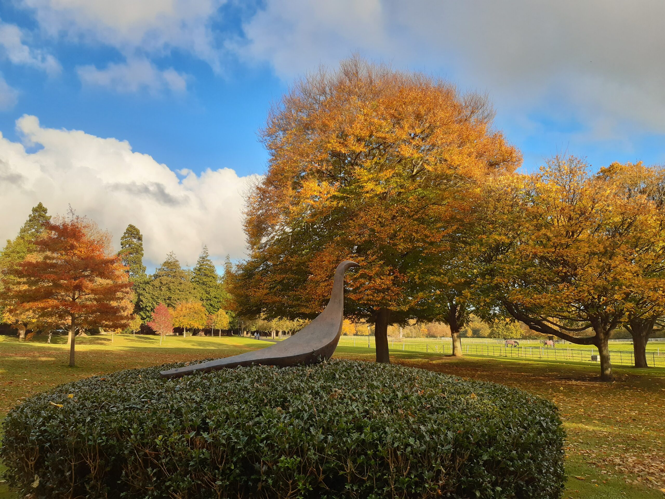 bronze bird sculpture surrounded by autumn trees