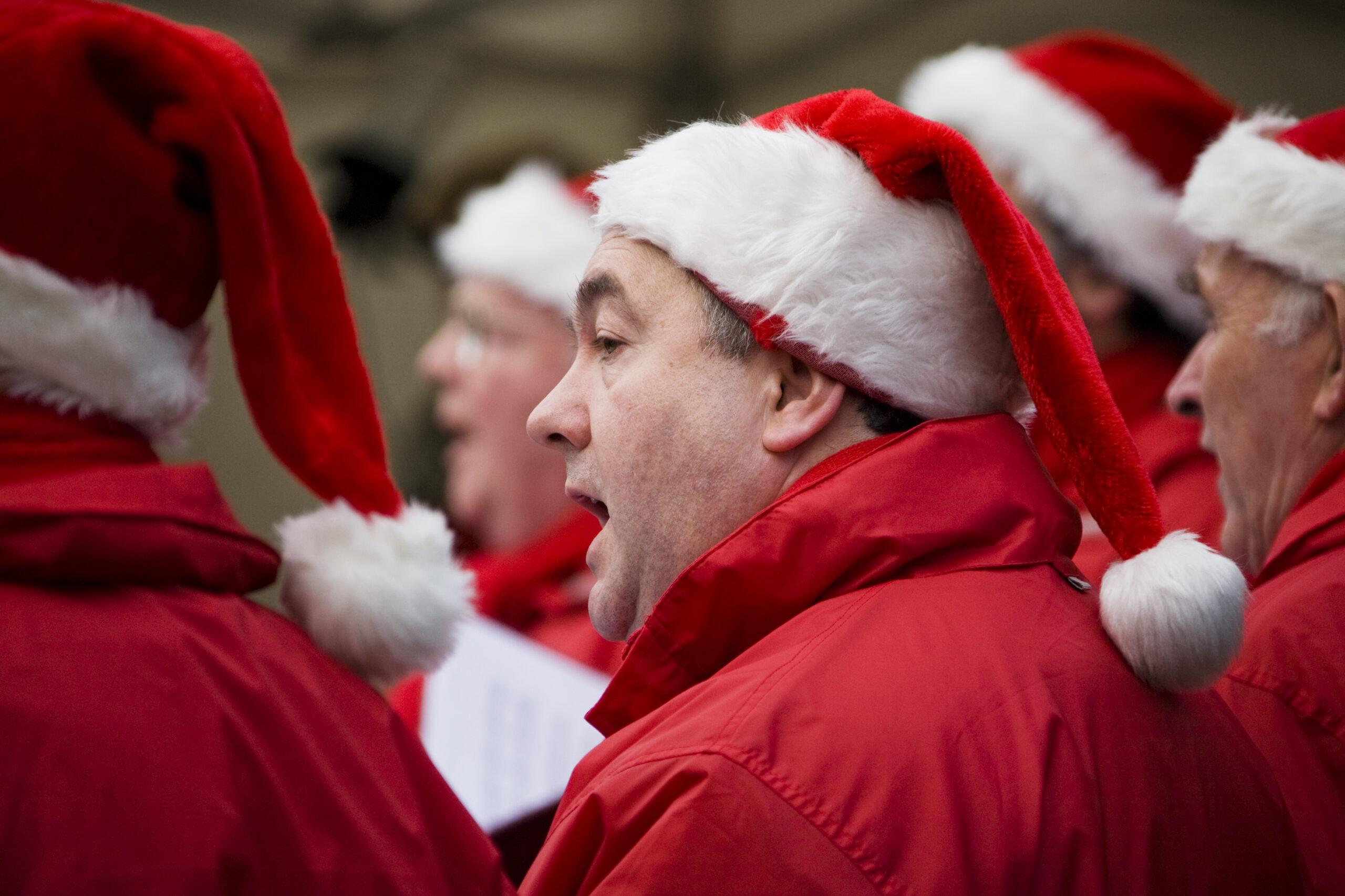 Close up photo of barbershop singers wearing Santa hats