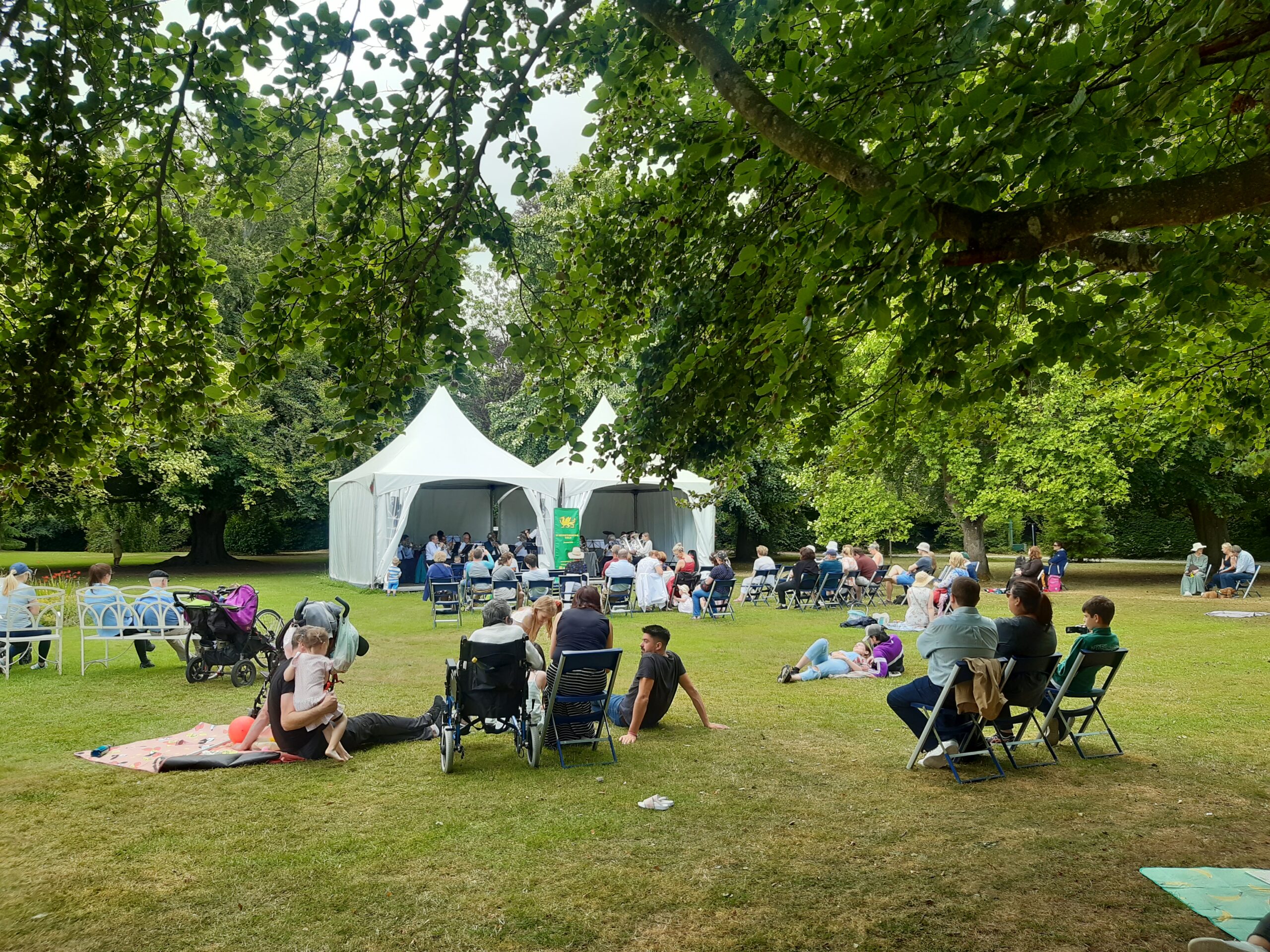People on lawn watching Brass Band perform in white tent